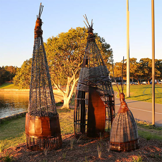 Three conical mixed-media sculptures in a public park.